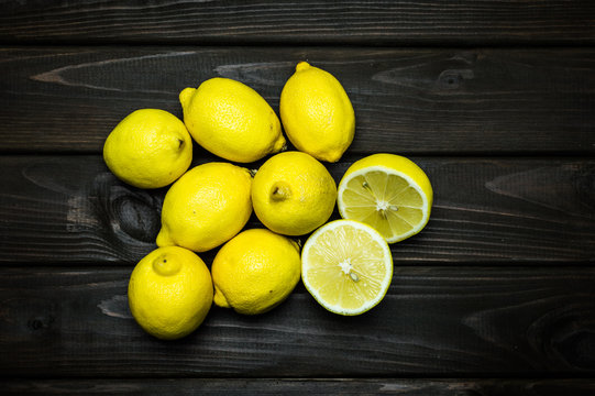 Whole and cut lemons on grey wooden surface