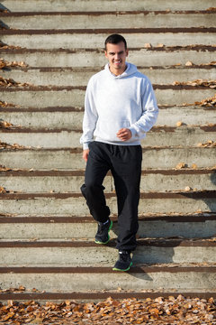 Young happy man jogging at stairs outdoors and smiling