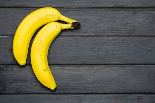 Yellow bananas on grey wooden surface