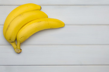 Yellow bananas from above a white wooden table