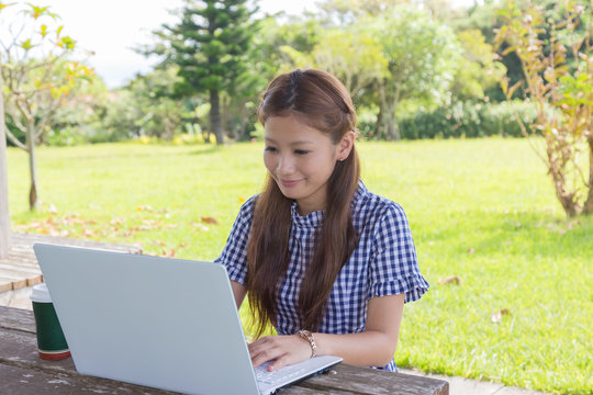 公園でパソコンを操作する若い女性