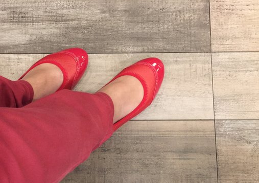 Woman with red shoe on wood floor background texture