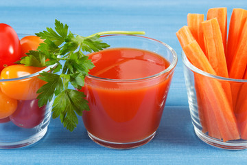 Tomato juice and vegetables on blue board, healthy nutrition