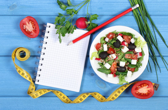 Greek salad with vegetables, centimeter and notepad for notes, healthy food and slimming concept