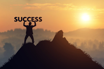 silhouette Man Holds a sign of success on mountain top over sky