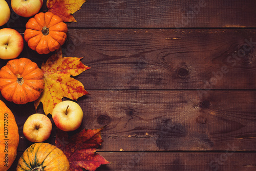 Thanksgiving background: Apples, pumpkins and fallen leaves on wooden background. Copy space for text. Halloween, Thanksgiving day or seasonal background. Design mock up.