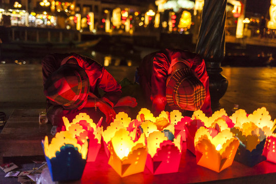 Bored guys sell paper lanterns to a tourist in Hoi An old town city, Vietnam