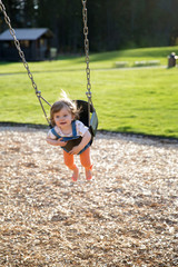 Cute baby girl having fun on a swing
