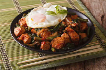 Spicy Stir-Fry Chicken with basil, green beans and a fried egg close-up horizontal