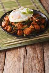 Spicy Stir-Fry Chicken with basil, green beans and a fried egg close-up vertical
