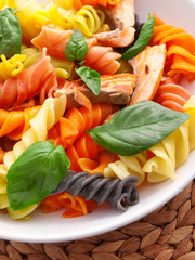 Colorful fusilli pasta with baked salmon and basil. Close up, ve
