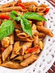 Whole wheat penne pasta with tomatoes and basil.Vertical shot