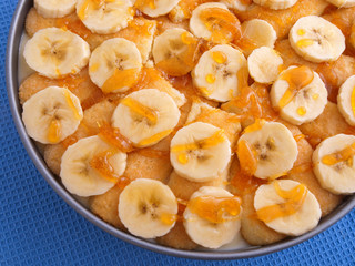 Homemade cake with bananas and caramel in a bowl. Shot on blue b