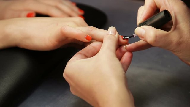 manicure making - female hands, covering of transparent enamel.Woman hands in a nail salon receiving a manicure by a beautician, nail polish. Woman getting nail manicure, body care, spa treatments