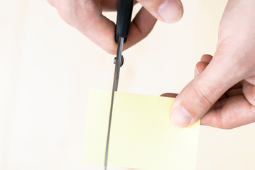 A man is cutting a sheet of yellow paper using metallic scissors