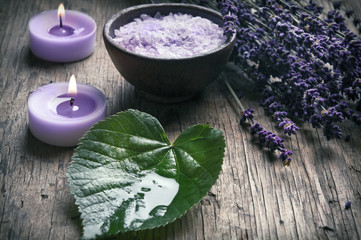 Obraz na płótnie Canvas Wellness concept with lavender, a green leaf, candles and bowl of salt in old style coloring
