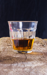glass of whiskey on a wooden table with a black background
