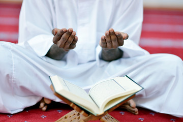 Obraz premium African Muslim Man Making Traditional Prayer To God While Wearing A Traditional Cap Dishdash