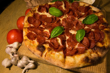 Pizza party fresh basil pepperoni tomatoes wooden cutting board on table
