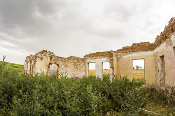 Fototapeta premium Parts of a ruined house with dramatic sky - different textures and herbs. Fisheye lens effect