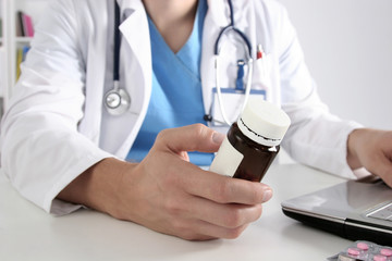 Male doctor sitting at the table and holding bottle