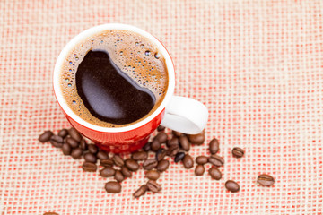 Coffee beans and cup with coffee with burlap texture