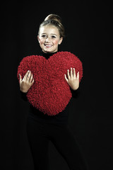 Teenage beautiful girl hugging red heard pillow