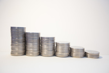 Silver coins stacked on a white background signifying various metaphors for finance and economics