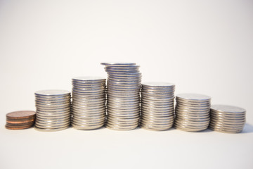 Silver coins stacked on a white background signifying various metaphors for finance and economics