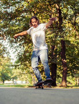 Skateboarder riding a skateboard on the last two wheels through the forest. Freeride skating
