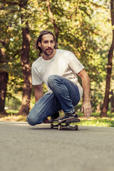 Obraz premium Skateboarder squatting on a skateboard and ride a slope on the road through the forest. Freeride skateboarding