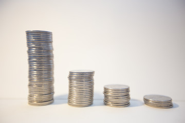 Silver coins stacked on a white background signifying various metaphors for finance and economics