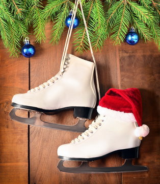 Christmas decoration. Skates and fir branch on wooden background.