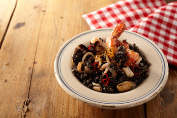 Fototapeta na wymiar Shellfish gourmet risotto nero meal in bowl beside napkin