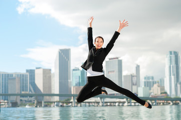 Fototapeta na wymiar Happy Businesswoman Leaping with Miami Skyline in Background
