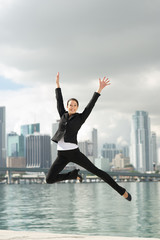 Fototapeta na wymiar Happy Businesswoman Leaping with Miami Skyline in Background