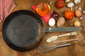 Kitchen iron pan and ingredients to prepare meals. Wooden spoons for cooking. Amenities of home cooking. Sales of kitchen tools.
