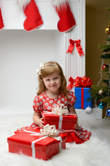 Child sitting with Christmas gifts in their hands near fireplace