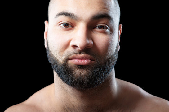 Power and confidence. Close up portrait of strong latino man with beard against black background.