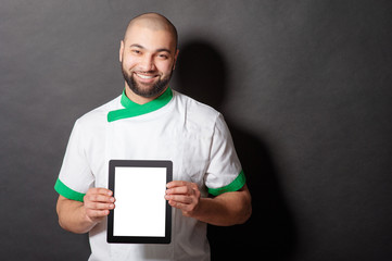 Digital menu. Handsome young arabic chief cook holding tablet computer against blackboard.