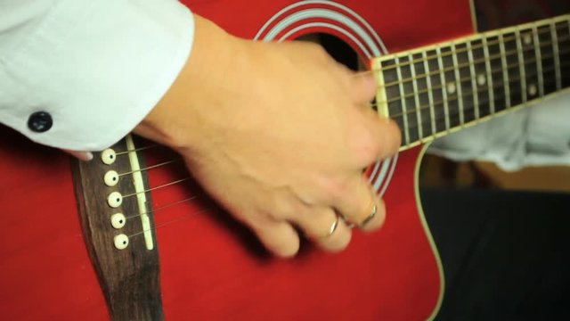 Guitarist playing on six-string acoustic guitar. Close up of hands and guitar strings.