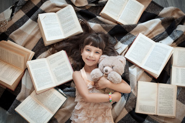 Fototapeta na wymiar cheerful little girl lying on floor with lot of books;