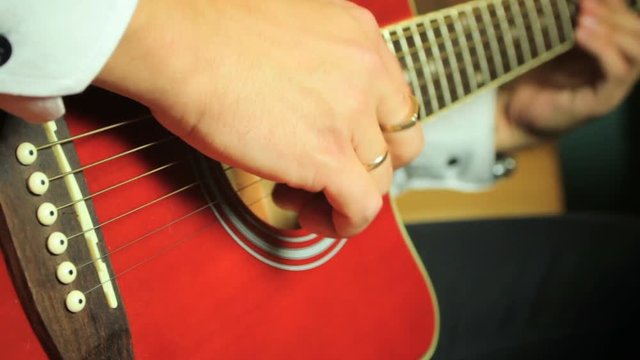 Guitarist playing on six-string acoustic guitar. Close up of hands and guitar strings.