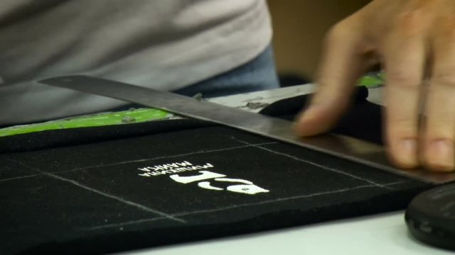 Cutting Printed on Fabric Logo Out Process. Male Worker Using Ruler and White Chalk. Black Material. Closeup
