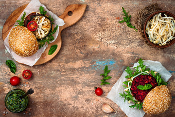 Two veggies burgers over stone vintage background. Vegan grilled eggplant, arugula, sprouts and pesto sauce burger. Veggie beet and quinoa burger. Top view, overhead, flat lay. Copy space