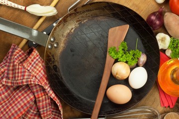Kitchen iron pan and ingredients to prepare meals. Wooden spoons for cooking. Amenities of home cooking. Sales of kitchen tools.
