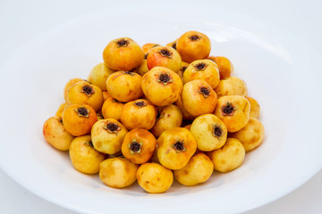 many yellow hawthorn on a white plate. in  studio