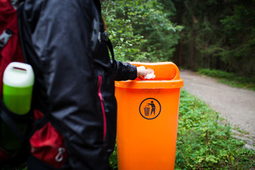 Young female tourist/woman/girl throwing  paper/napkin/handkerchief in recycling bin, isolated...