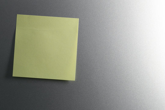 Empty yellow paper sheet on refrigerator door for design.