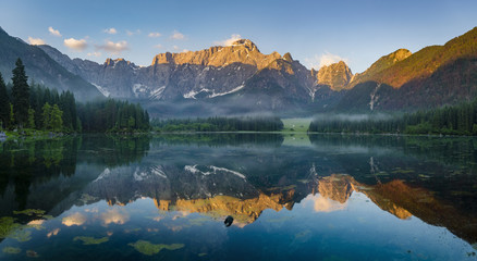 reflection of  mountain Mangart in a mountain lake Laghi di Fusine at sunrise, Julian Alps, Italy
